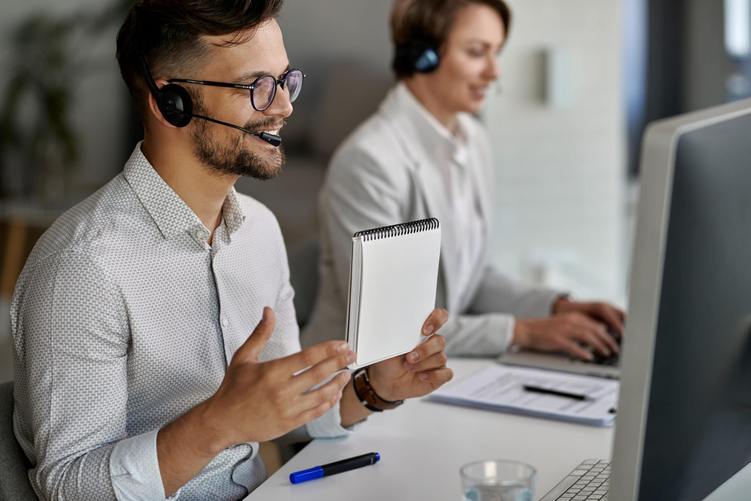 Happy customer service representative using computer and having video call with clients while working at call center.